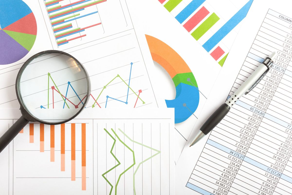 Magnifying glass over printed ranking charts and a spreadsheet of website traffic data